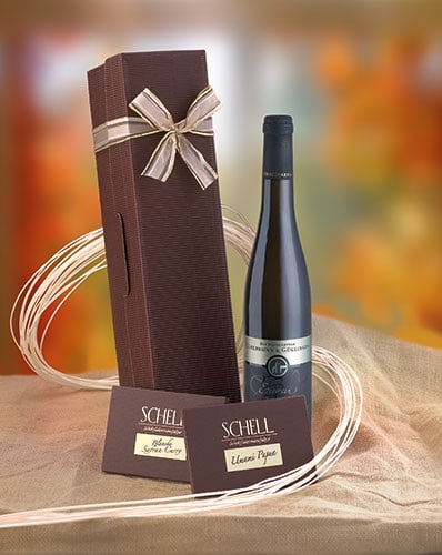 Geschenkpaket „Eiswein“ ohne Pralinen mit je einer Tafel Umami Papua und Blanche Safran Curry in einer braunen Verpackung und einer Flasche Wein.