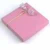 16er Schatulle "Rosenzauber" von Schell Schokoladen hat eine pinke Verpackung mit einer pinken Schleife an einem Strohband.