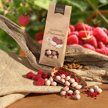 Die Himbeermandeln von Schell Schokoladen haben eine braune Papierverpackung. Mandeln mit weißer Schokolade, Himbeeren und rotem Pfeffer. Genießen Sie unsere Himbeermandeln gekühlt zu einem Glas Rose.