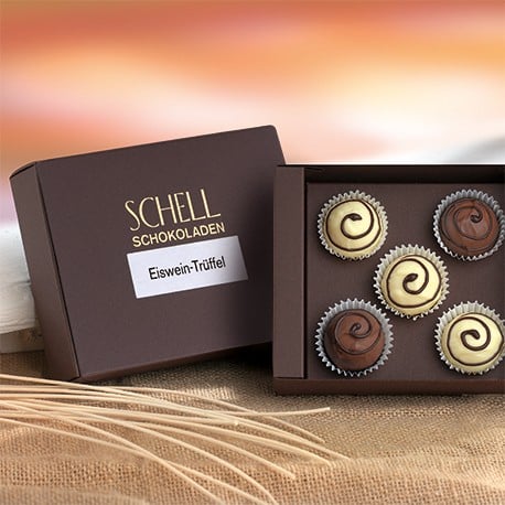 Eiswein- und TBA Trüffel von Schell Schokoladen befinden sich in einer 5er Schachtel mit einer braunen Verpackung, auf dem Deckel steht das Schell Logo und drunter die Pralinensorte.