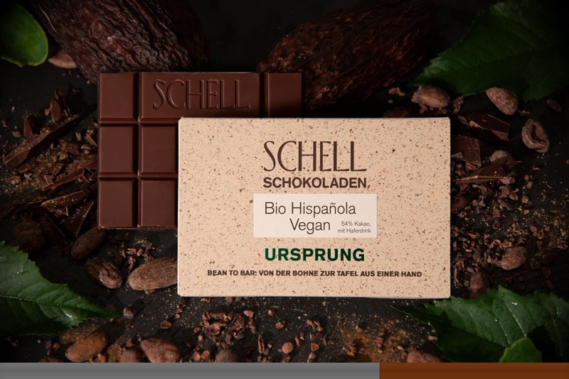 Es ist die Bio Hispanola vegan Schokolade zu sehen über der Schokolade ist die beige Verpackung wo der Name und unser Logo abgebildet ist.