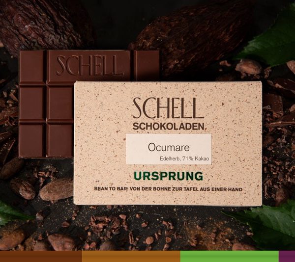 Es ist die Ocumare Schokolade zu sehen über der Schokolade ist die beige Verpackung wo der Name und unser Logo abgebildet ist.