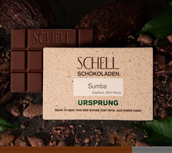 Es ist die Sumba Schokolade zu sehen über der Schokolade ist die beige Verpackung wo der Name und unser Logo abgebildet ist.