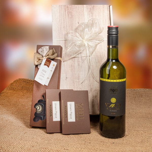 Geschenkpaket „Vinum“ mit Pralinen enthält jeweils zwei Tafeln Umami Papua in einer braunen Verpackung. Zudem gibt es einen Riesling Wein und eine 14er Schachtel mit der Kreation "Rund um den Wein" in einer braunen Verpackung mit einer braunen und weißen Schleife.